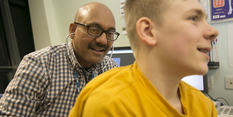Prof Somnath Mukhopadhyay with a patient in a yellow tshirt assessing asthma